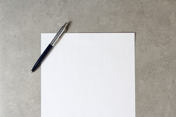 Template of white paper with a ballpoint pen on light grey concrete background. Concept of new idea, business plan and strategy. Stock photo with empty space for text