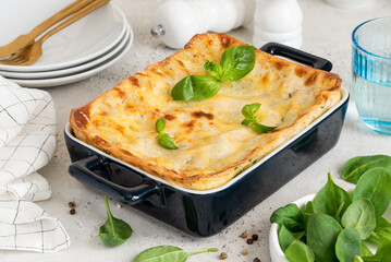 Homemade lasagna with spinach and ricotta in a blue ceramic mold. Traditional italian dish. Selective focus