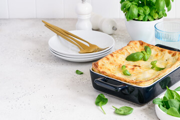 Homemade lasagna with spinach and ricotta in a blue ceramic mold. Traditional italian dish.  Selective focus. Copy space