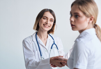 Fototapeta premium beautiful woman doctor with stethoscope shaking hands with female patient 
