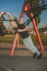 Fototapeta premium Young man with braided mohawk hairstyle doing exercise outdoors using overhead training