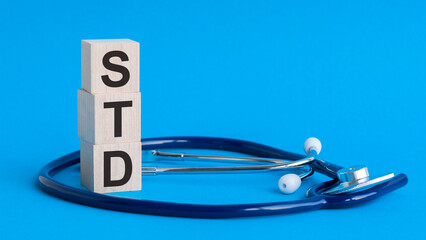 std word written on wooden blocks and stethoscope on light blue background