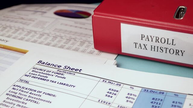 Balance sheet summary form and Folder with Documents of Payroll tax history on the background of financial documents, close-up
