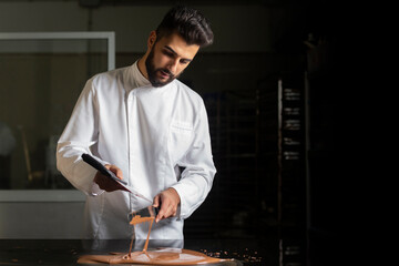 Pastry chef working on tempering chocolate on marble table