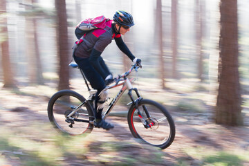 Man riding a mountain bike in a forest on a sunny day with fog