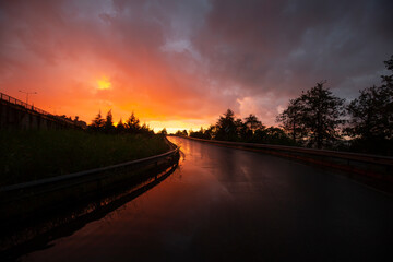 Obraz premium wet reflected road in sunset