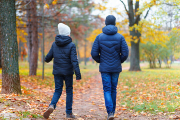 Fototapeta premium teen girl and boy walking through the park and enjoys autumn, beautiful nature with yellow leaves