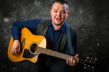 Mature musician plays acoustic guitar emotional studio portrait.