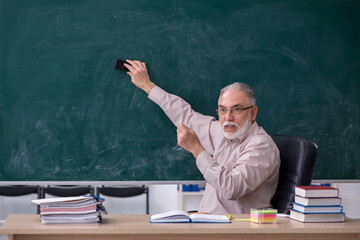 Old male teacher sitting in the classroom