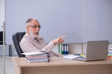 Old male teacher sitting in the classroom