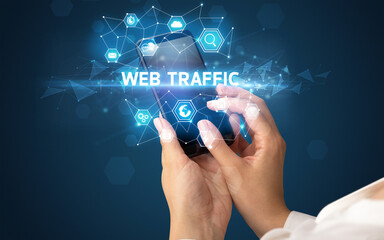Female hand holding smartphone with WEB TRAFFIC inscription, modern technology concept