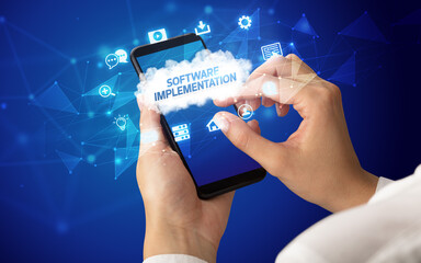 Female hand holding smartphone with SOFTWARE IMPLEMENTATION inscription, cloud technology concept