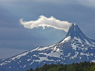 A cloud near the top of a snowy Solvågtinden mountain at Junkerdal National park, Nordland, Norway