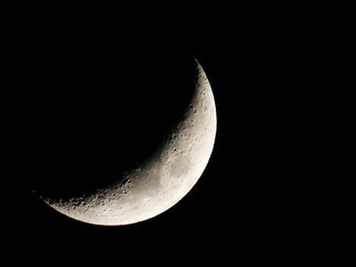 Young growing moon close up against the black sky
