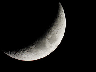 Young growing moon close up against the black sky