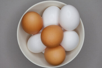 Brown and white chicken eggs in a ceramic bowl