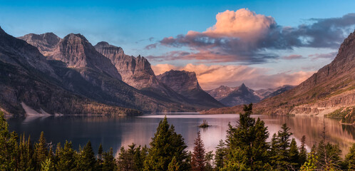 Beautiful Panoramic View of a Glacier Lake with American Rocky Mountain Landscape in the background. Dramatic Colorful Sunrise Sky. Taken in Glacier National Park, Montana, United States. - obrazy, fototapety, plakaty
