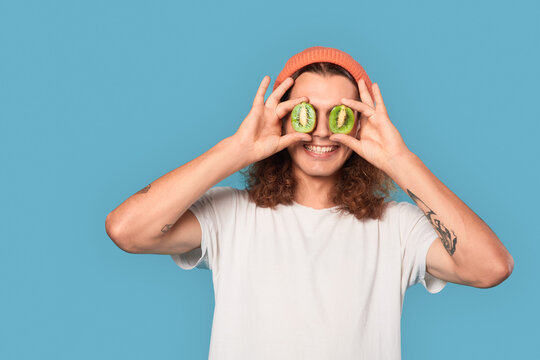 Young adult guy covered eyes with kiwi fruit