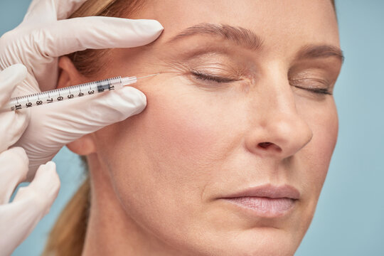 Close Up Portrait Of A Beautiful Mature Woman Keeping Eyes Closed While Receiving Hyaluronic Acid Injection By Beautician