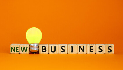 Time to new business. Wooden cubes with words 'new business'. Yellow light bulb. Beautiful orange...