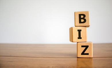 Business concept success process. Wooden cubes with a word 'biz' stacking as step stair on beautiful wooden table, white background. Copy space. Biz concept.