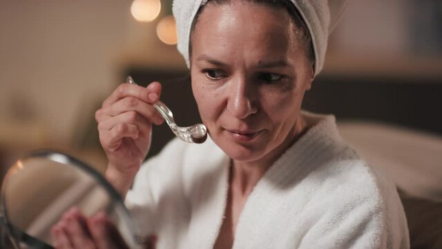 Close-up Of Attractive Smiling Woman Looking At Mirror While Rubbing Ice Cube On Skin Doing Beauty Evening Routine After Bath