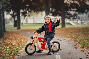 little boy riding a balance bike in the city in autumn