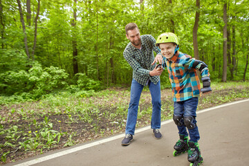 Obraz premium Father and son in the open air, preparing for roller skating. Father's Day.