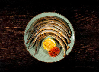 Grilled fish on a plate. Restaurant food. Fish dish with lemon. Seafood on a wooden background. Top view.
