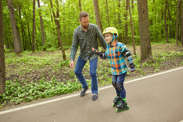 Father and son in the open air, preparing for roller skating. Father's Day.