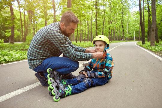 Father and son in the open air, preparing for roller skating. Father's Day.