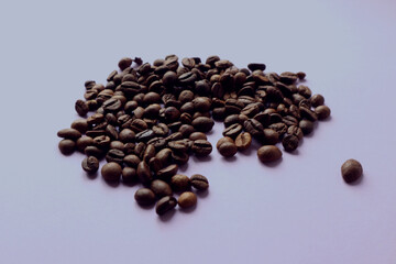 Coffee beans lie on the light kitchen table, side view, tinted in pastel color