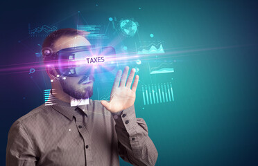 Businessman looking through Virtual Reality glasses with TAXES inscription, new business concept