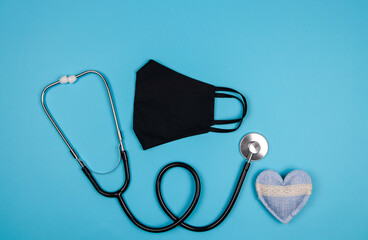 stethoscope and heart.

Stethoscope, medical mask and heart lie in the middle on a blue background, top view close-up.