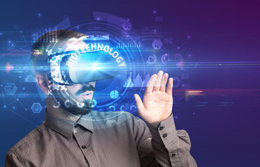 Businessman looking through Virtual Reality glasses with BIOTECHNOLOGY inscription, innovative technology concept