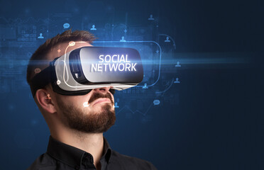 Businessman looking through Virtual Reality glasses with SOCIAL NETWORK inscription, social networking concept