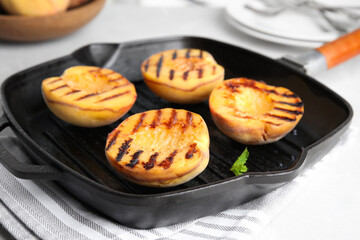 Delicious grilled peaches on light table, closeup