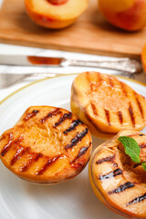 Delicious grilled peaches with mint on plate, closeup