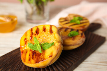 Delicious grilled peaches with mint on wooden board, closeup