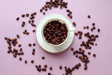 White Cup full of coffee beans on a pastel background and with scattered grains on it, top view - the concept of a pleasant coffee drinking