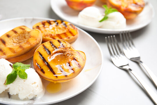 Delicious grilled peaches with ice cream and honey on grey table