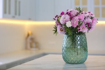 Vase with beautiful chrysanthemum flowers on table in kitchen, space for text. Interior design