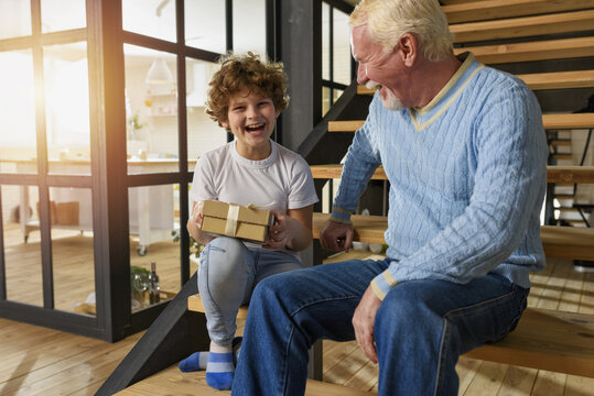 Happy grandson receives a gift from grandfather. joyful expression