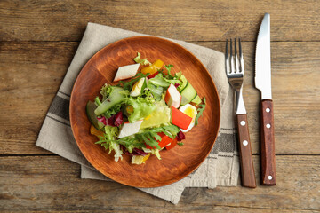 Delicious salad with crab sticks and lettuce served on wooden table, flat lay