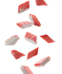 Cut fresh crab sticks falling on white background