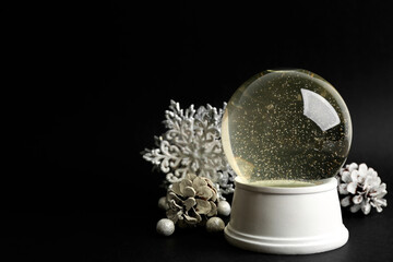 Beautiful empty snow globe and Christmas decor on black background, space for text