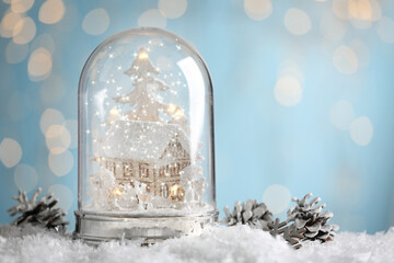 Beautiful snow globe and cones against blurred Christmas lights. Space for text