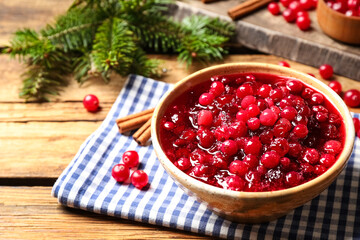 Fresh cranberry sauce in bowl on wooden table, space for text