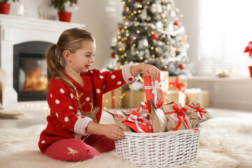 Obraz na płótnie Canvas Cute little girl taking gift from Christmas advent calendar at home