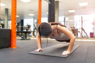 Fototapeta na wymiar Young woman doing push ups in a gym